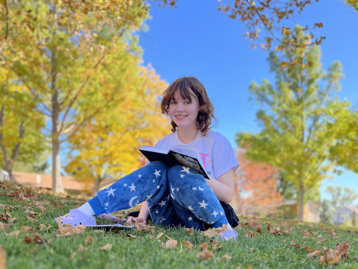 Student reading a book in a park setting.